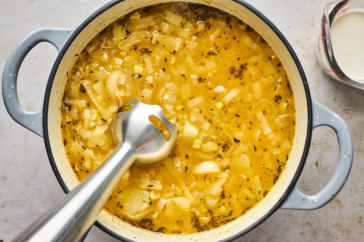 potato leek soup in large pot getting ready to be blended with immersion blender.