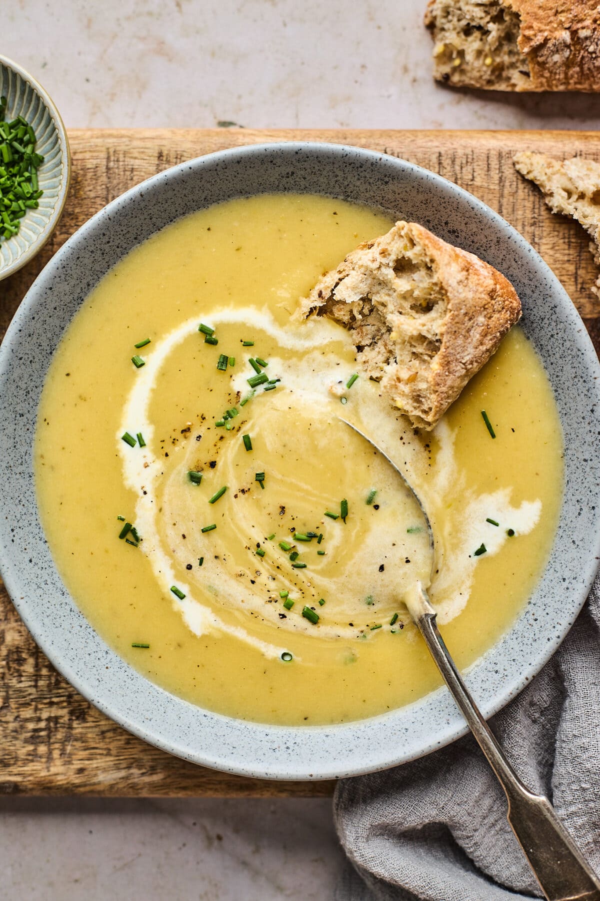 potato leek soup in bowl with chives and crusty bread. 