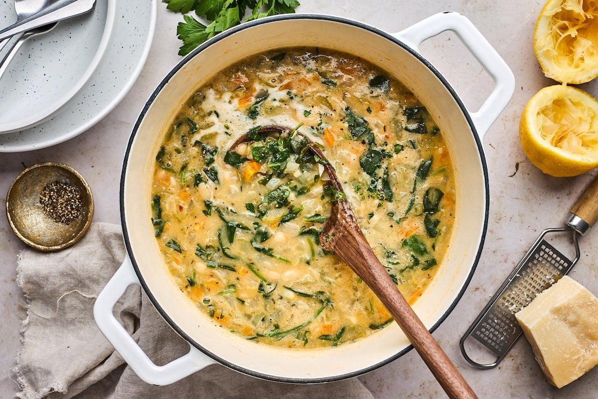 white bean soup in white pot with wooden spoon. 