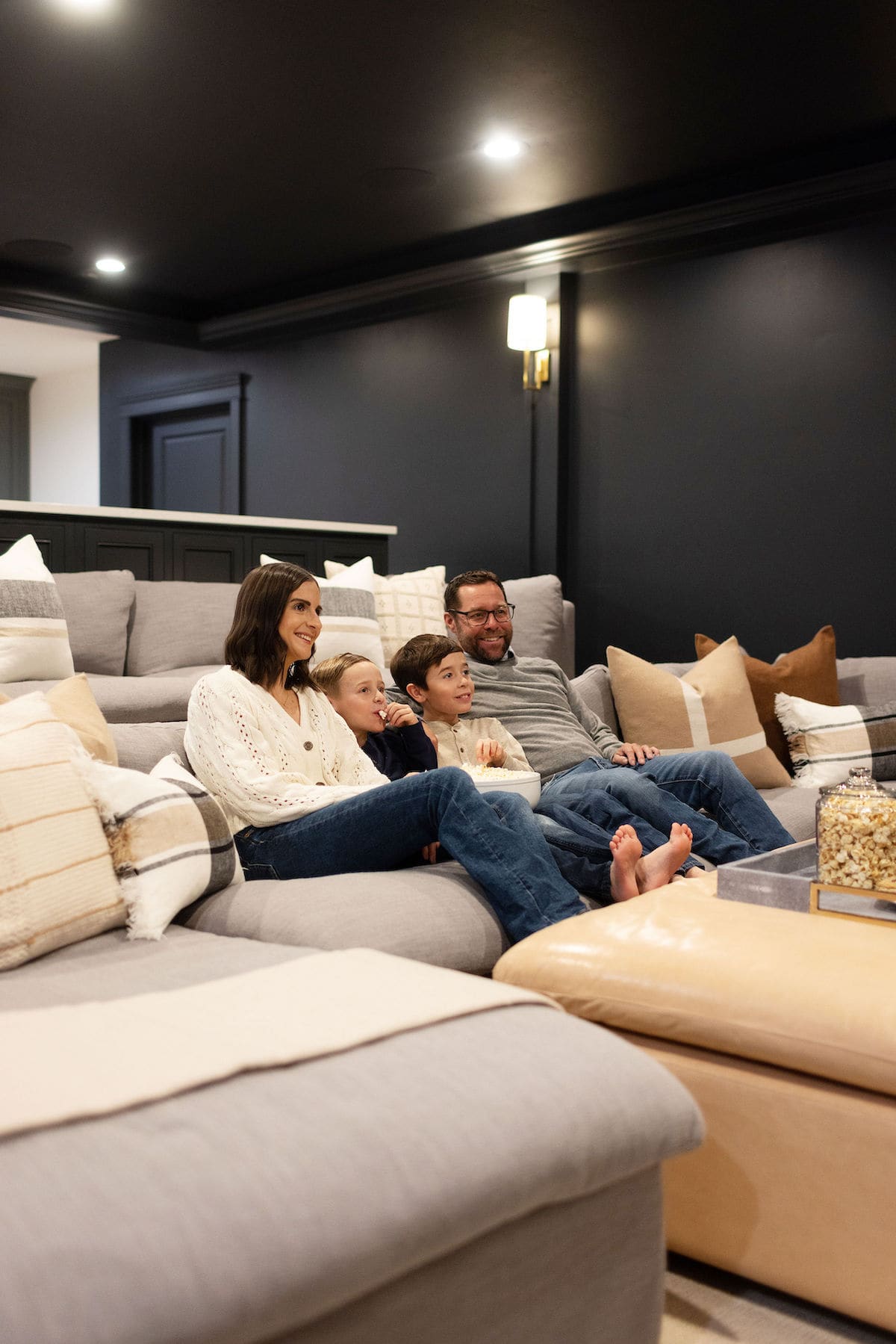 family watching movie in basement theatre room with popcorn. 