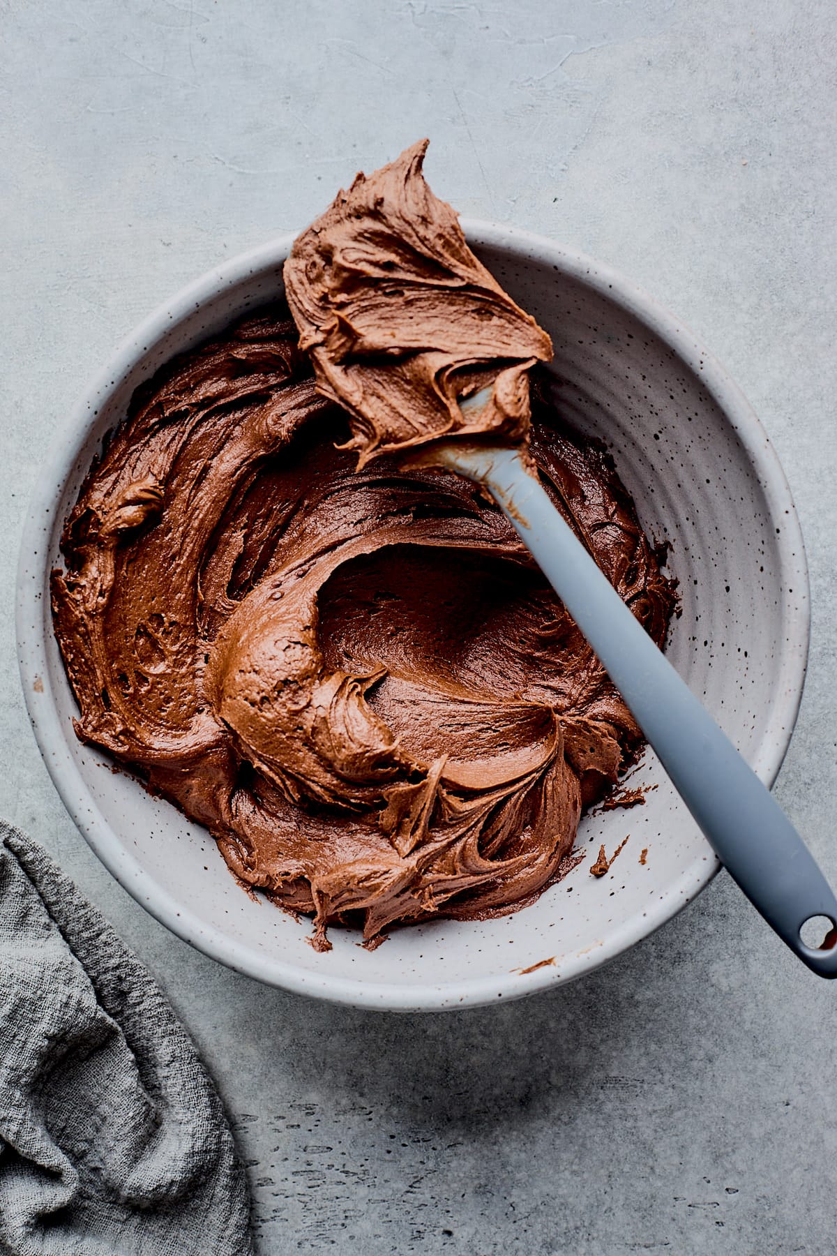 chocolate frosting in bowl with spatula. 