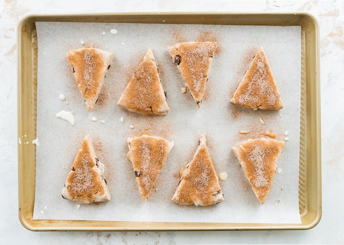 unbaked cinnamon raisin scones on large baking sheet with parchment paper.