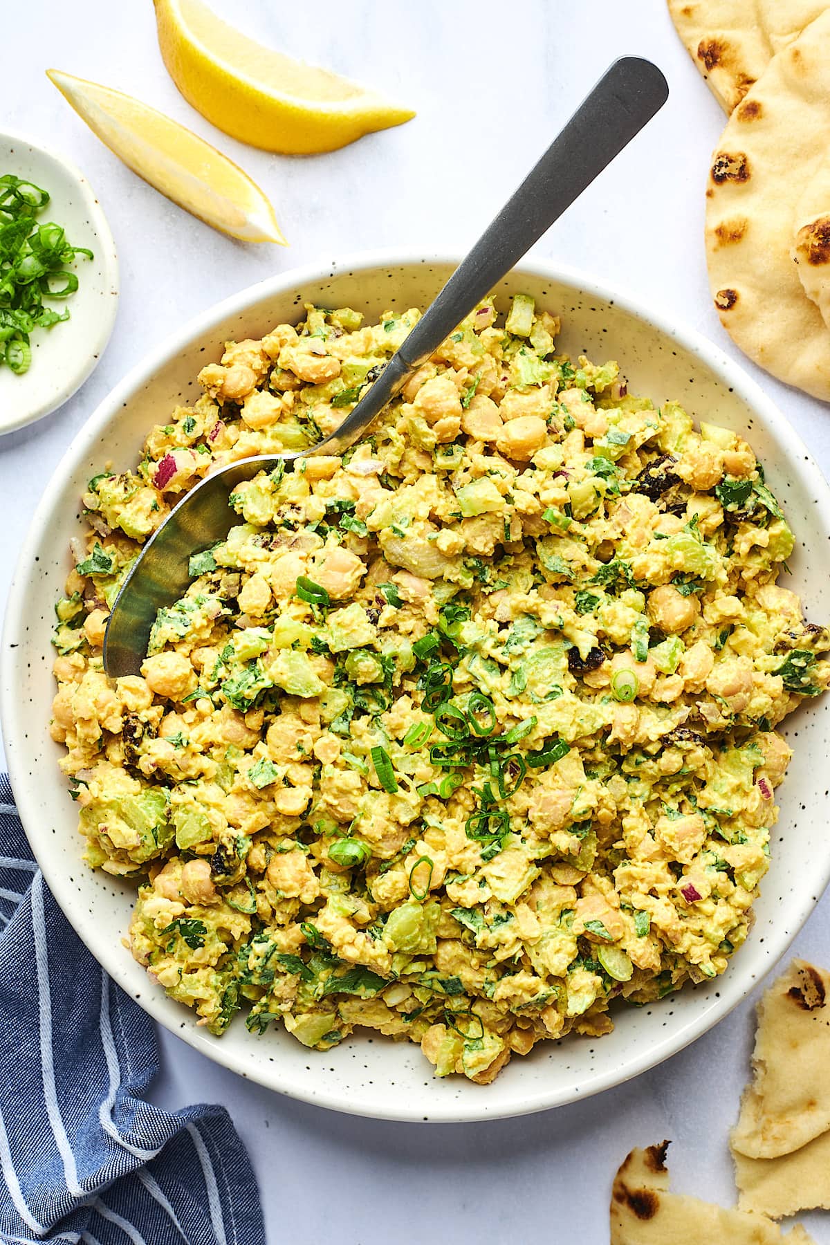 curried chickpea salad in large white bowl with spoon. 
