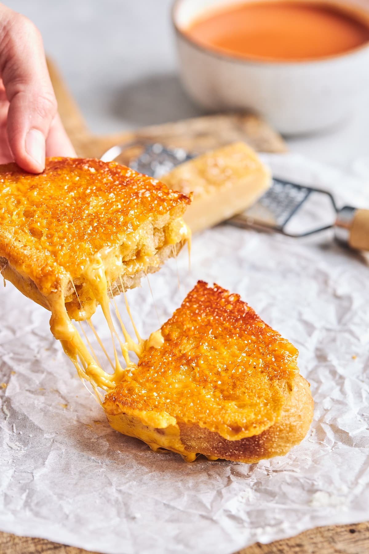 cheese crusted grilled cheese sandwich cut in half and being pulled apart with a cheese pull. 