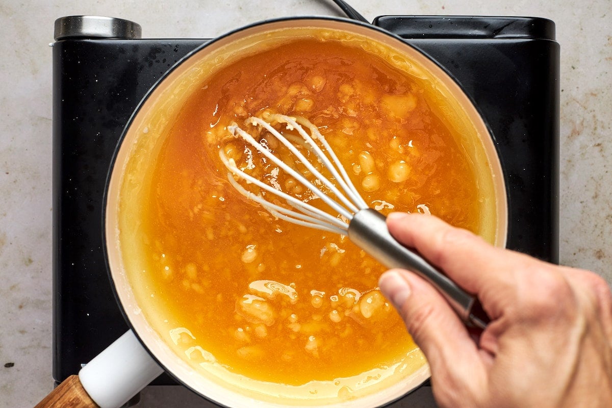 whisking salted caramel sauce in pan on stove. 