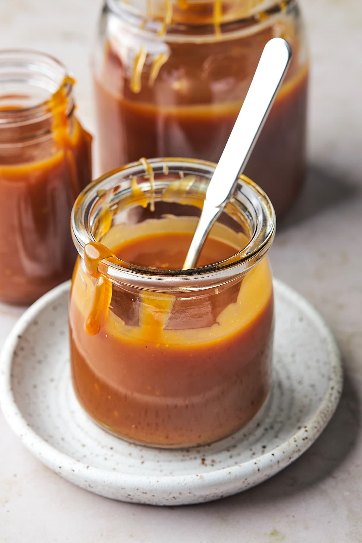 salted caramel sauce in jar with a spoon. 