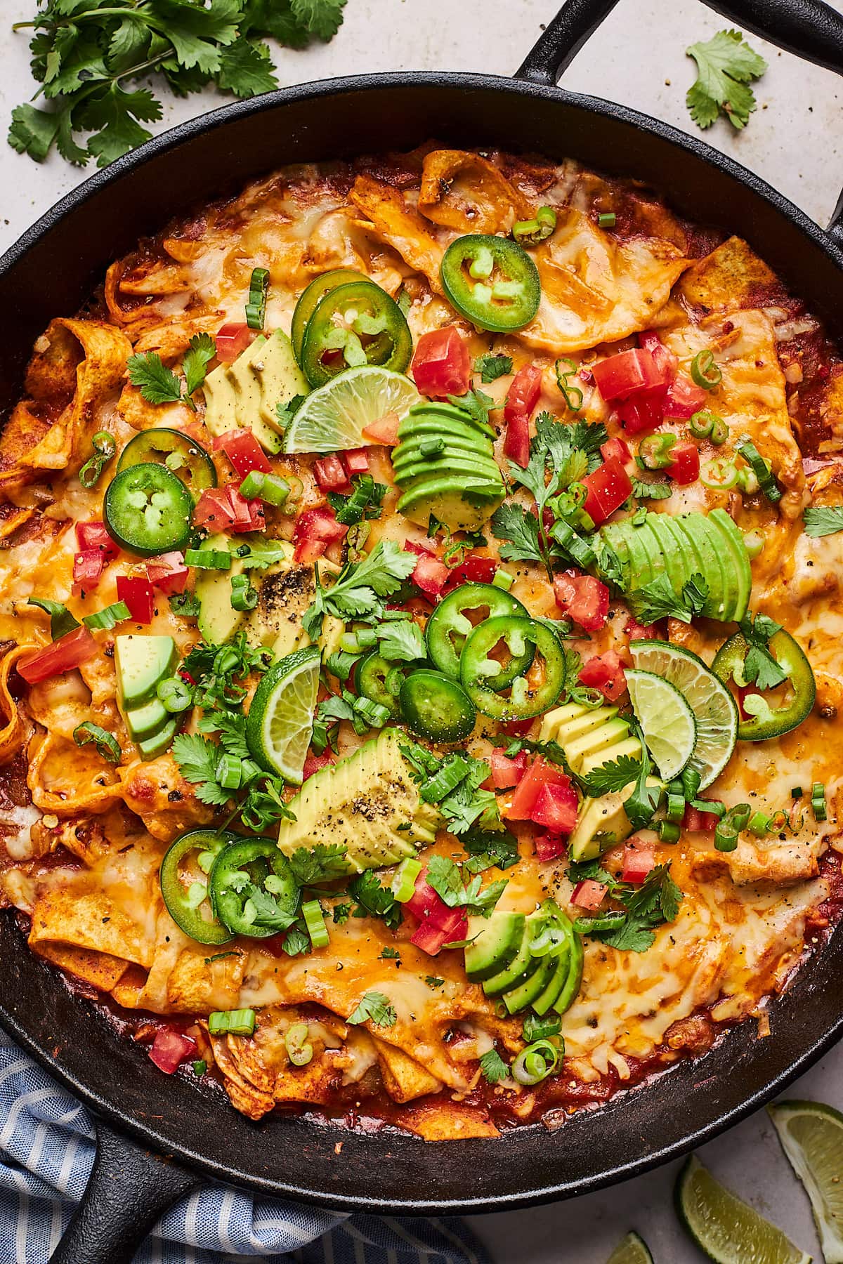 cheesy skillet chicken enchiladas with toppings in cast iron skillet. 
