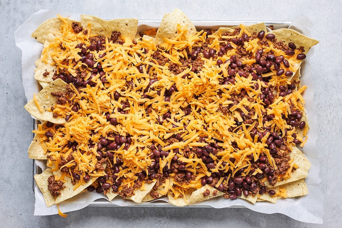tortilla chips on sheet pan with cheese, ground beef, and beans. 