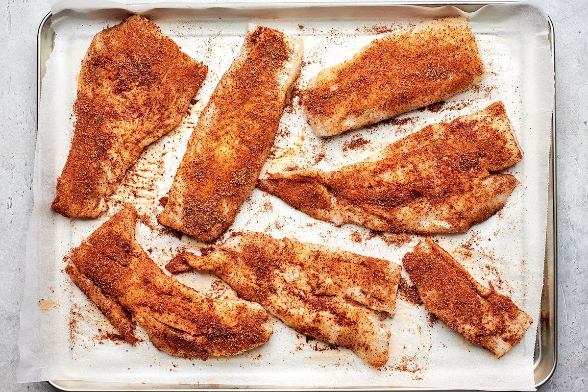 cod with taco seasoning on sheet pan with parchment paper. 