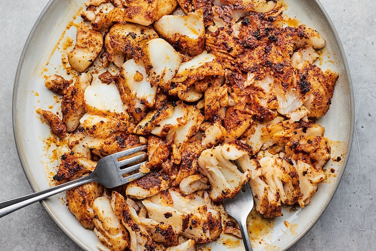 fish taco meat on plate being shredded with two forks. 