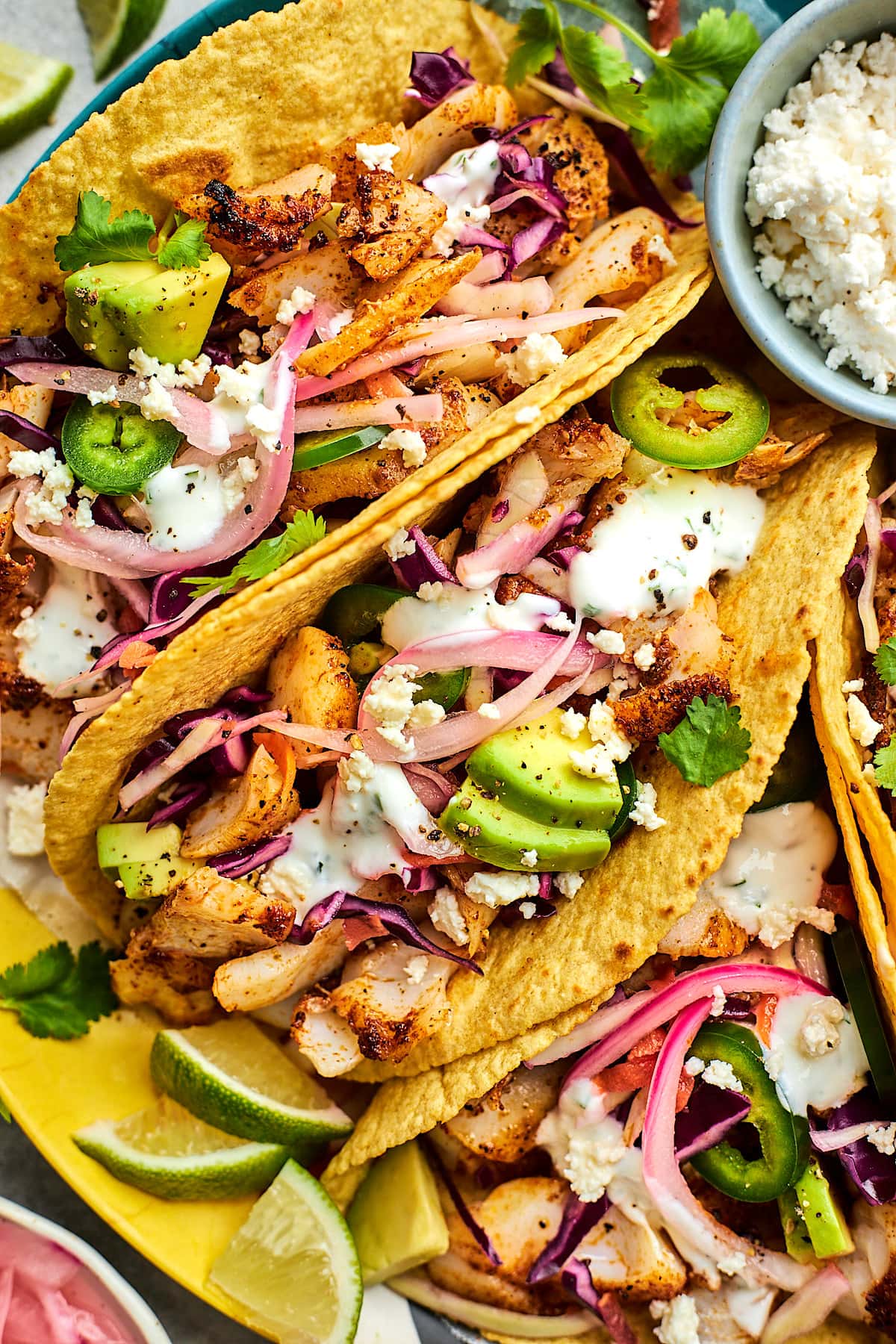 fish tacos in corn tortillas with lime crema, pickled red onions, avocado, cilantro, and cotija cheese. 