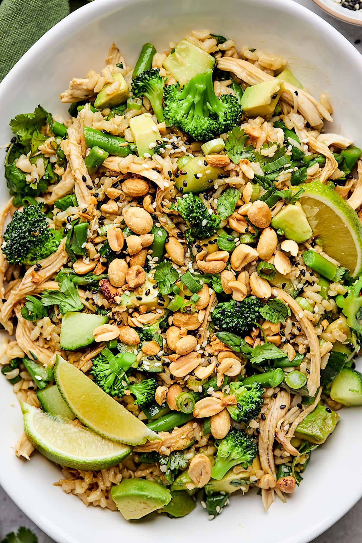 sesame ginger salad with chicken and vegetables with lime wedges in white bowl. 