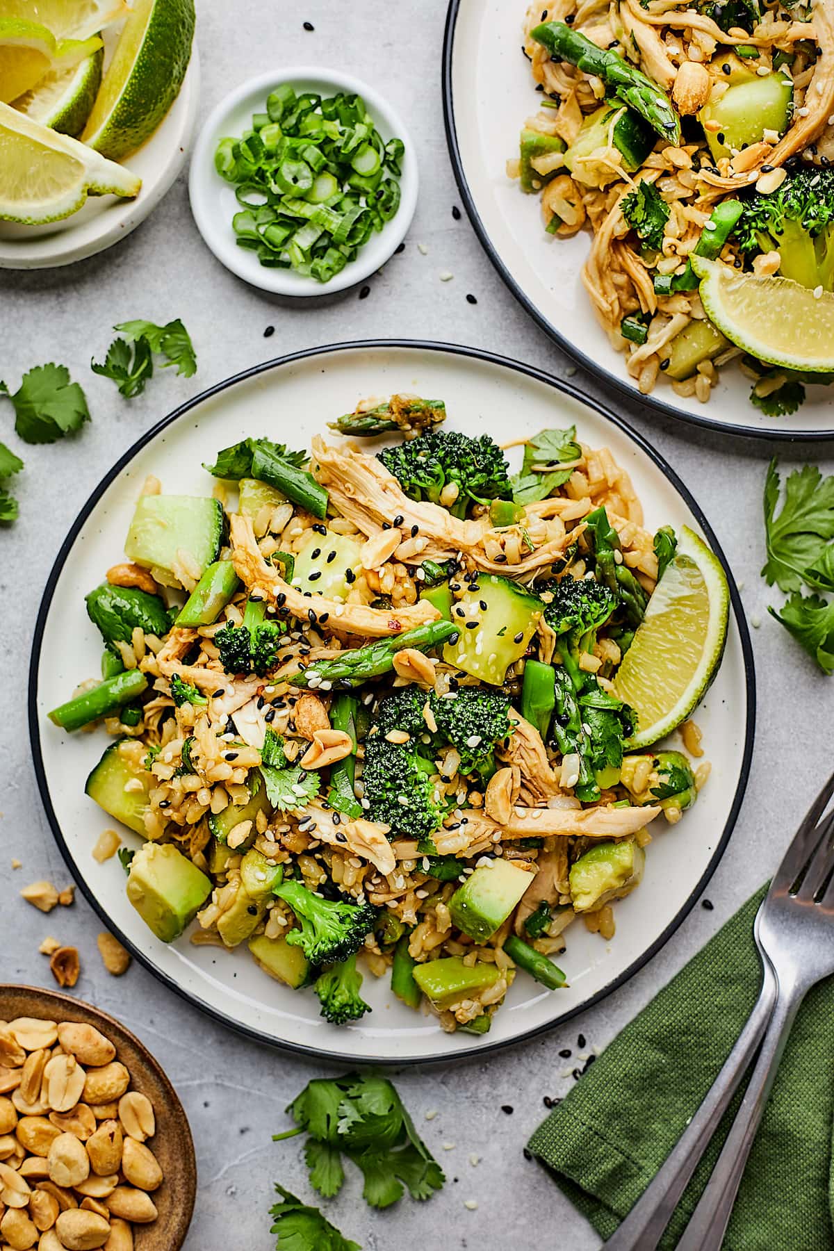 sesame ginger rice salad with chicken and vegetables on plates with forks and napkin.