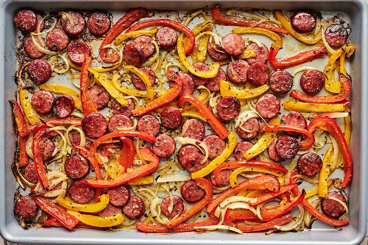 cooked sliced sausage rounds, peppers, and onions on large sheet pan. 