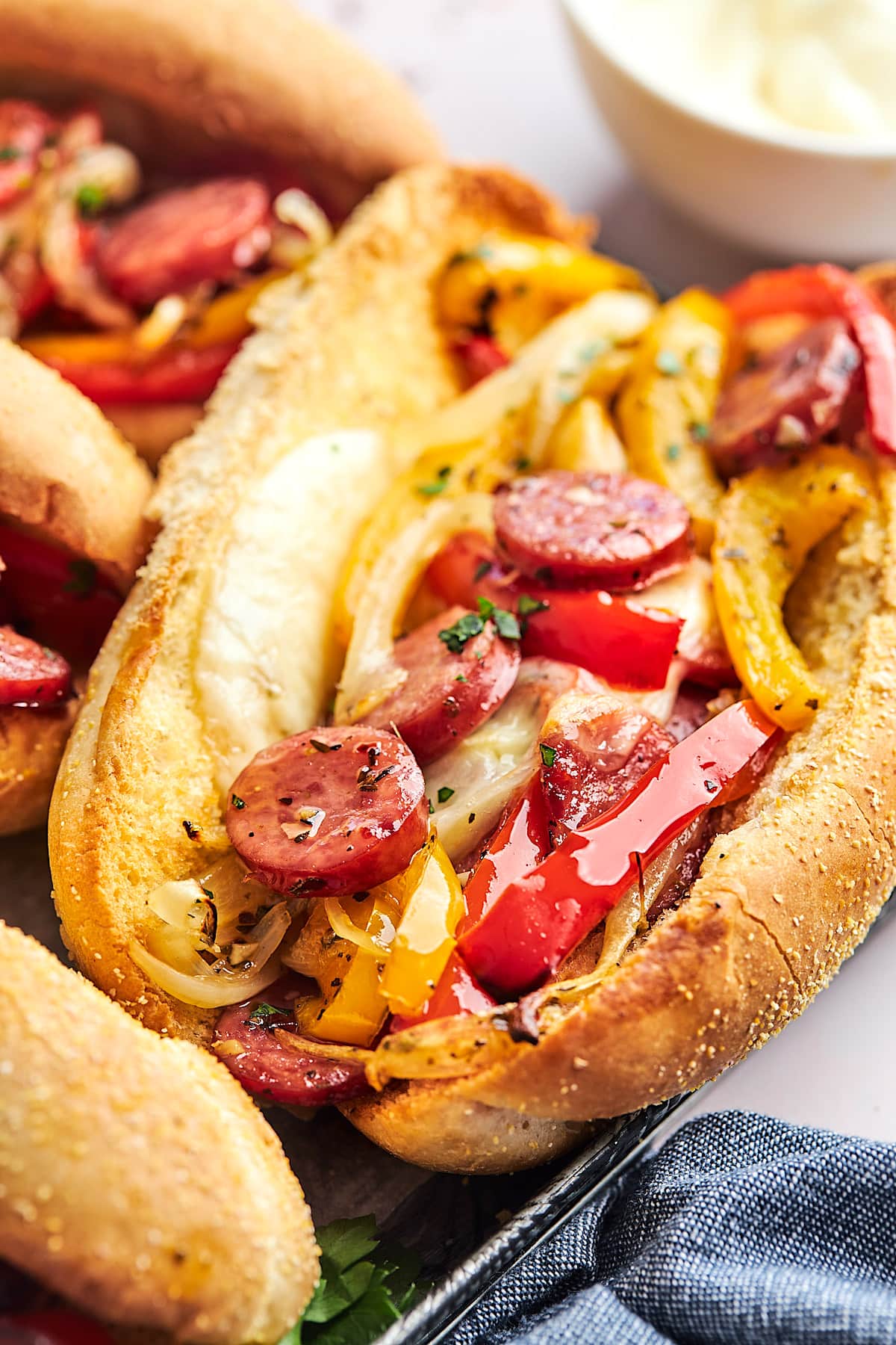 close up of sausage and peppers hoagie with melted provolone cheese.