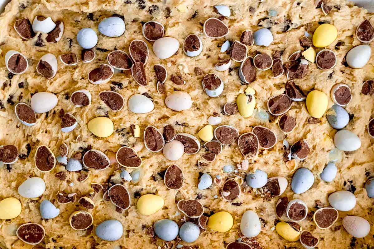 blondie dough pressed in pan with Cadbury mini eggs. 