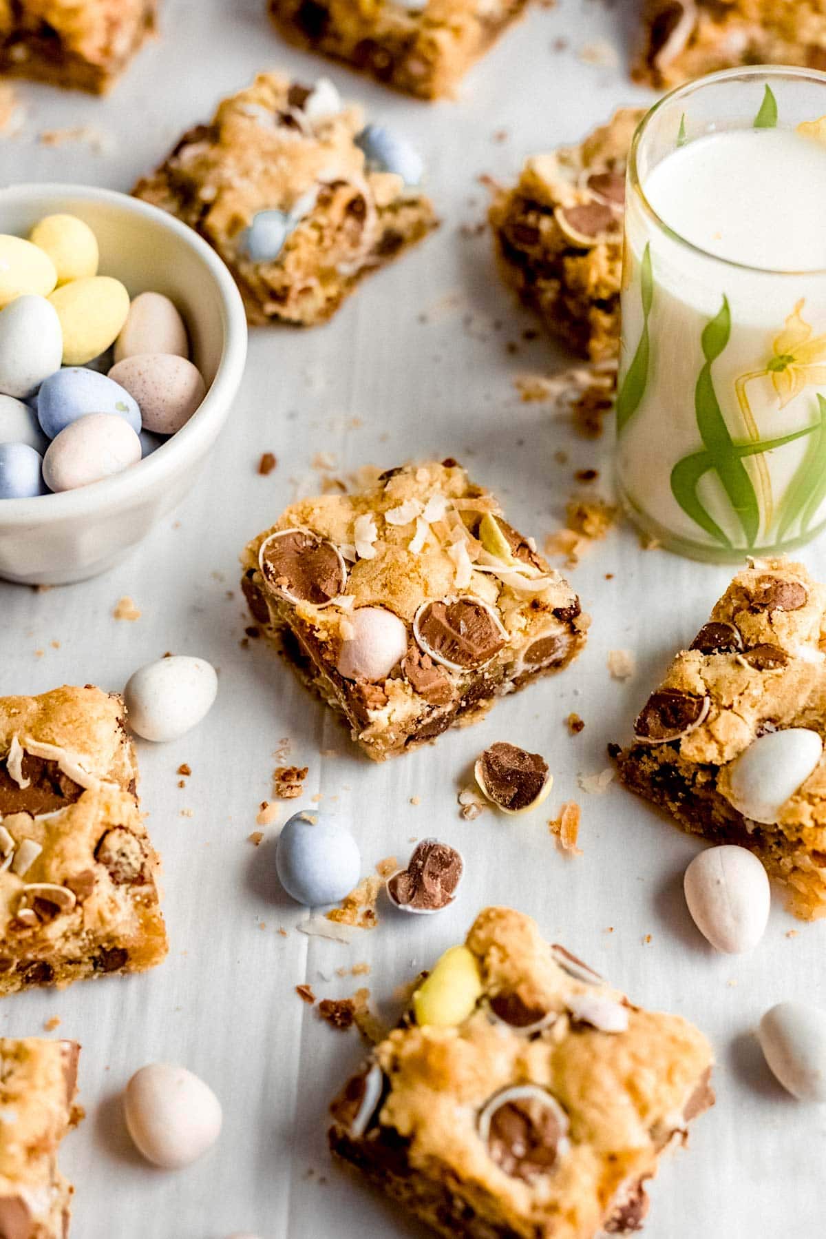 Cadbury blondies cut in squares with bowl of Cadbury mini eggs and glass of milk. 