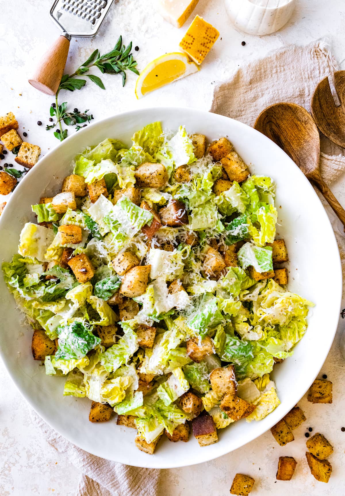 Caesar salad with croutons and parmesan cheese in large white bowl. 