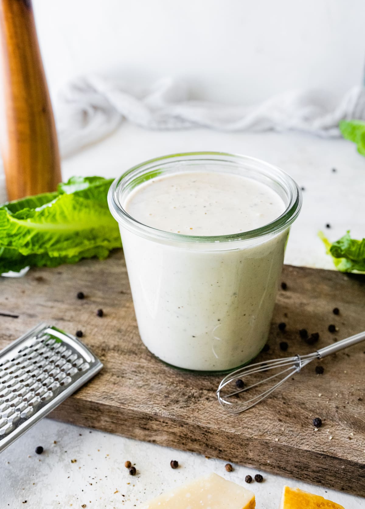 caesar dressing in a glass jar on wood board. 