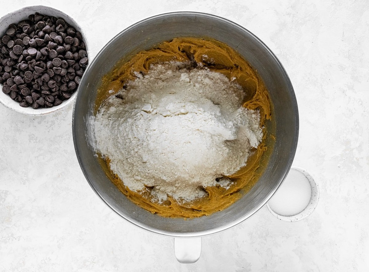 dry ingredients being added to peanut butter cookie dough in mixing bowl. 