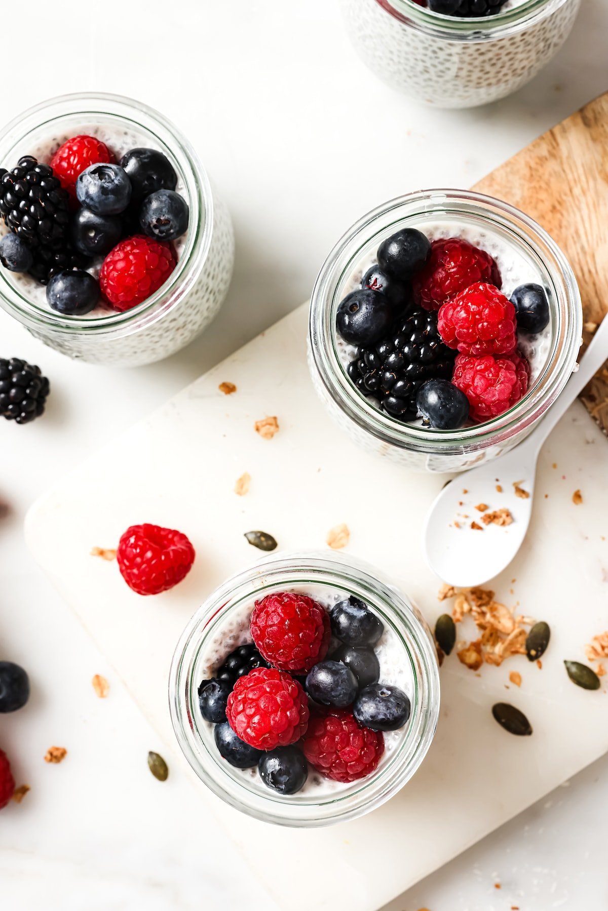 chia pudding in 3 jars with berries on top. 