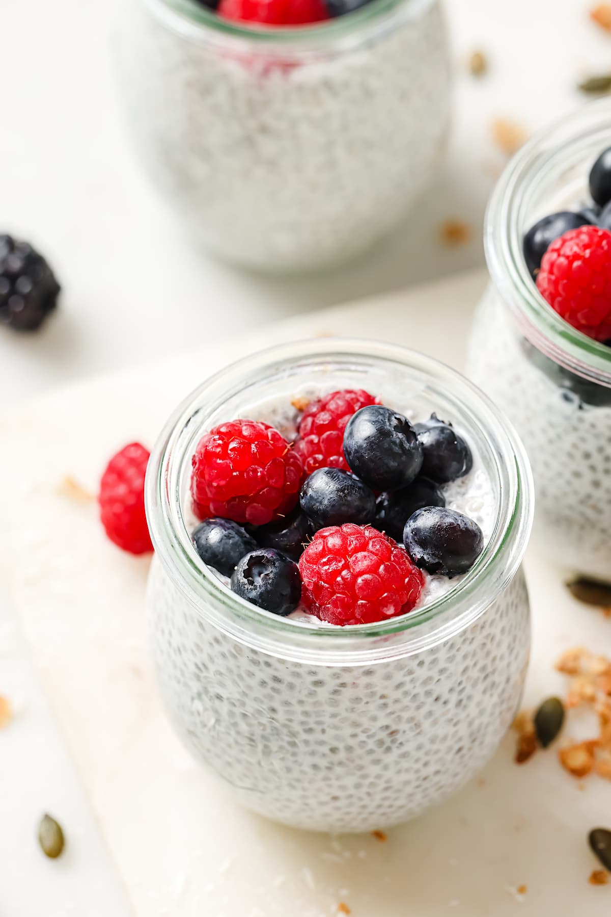 chia pudding in small glass jar with berries on top. 