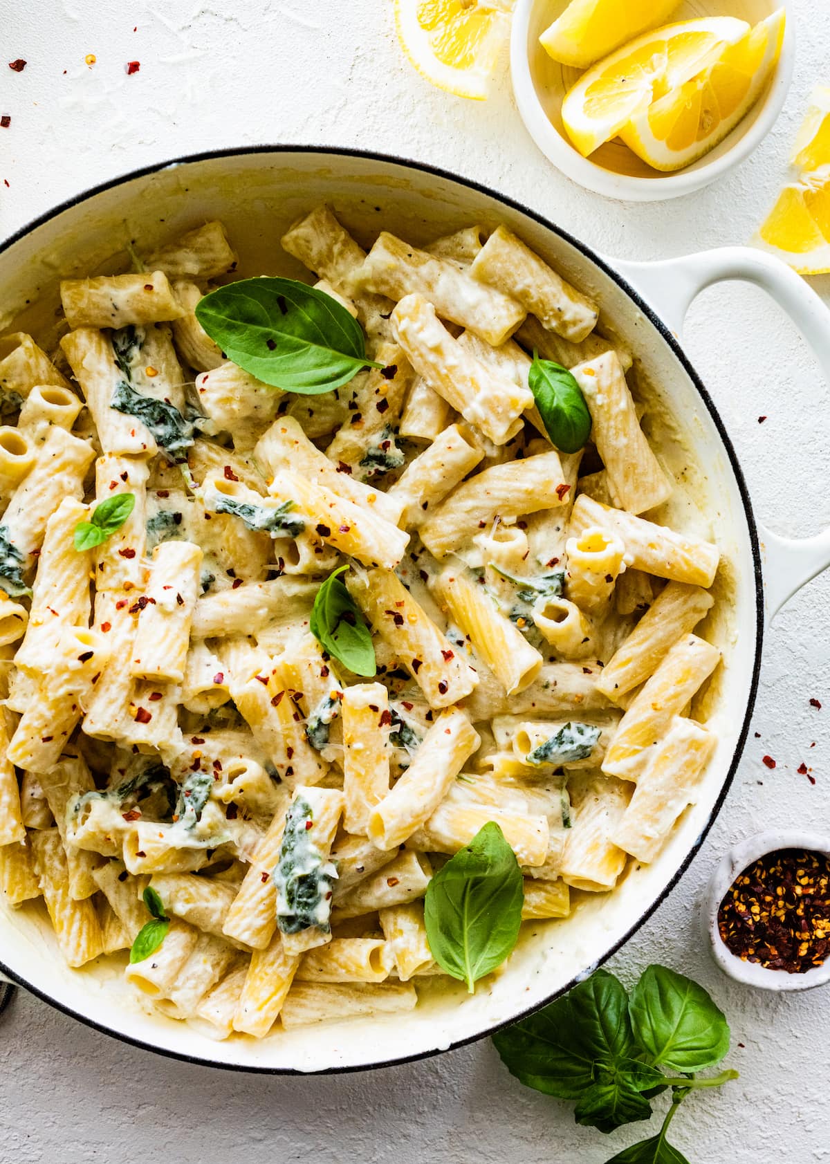 lemon ricotta pasta in pot with spinach, basil, and crushed red pepper flakes. 