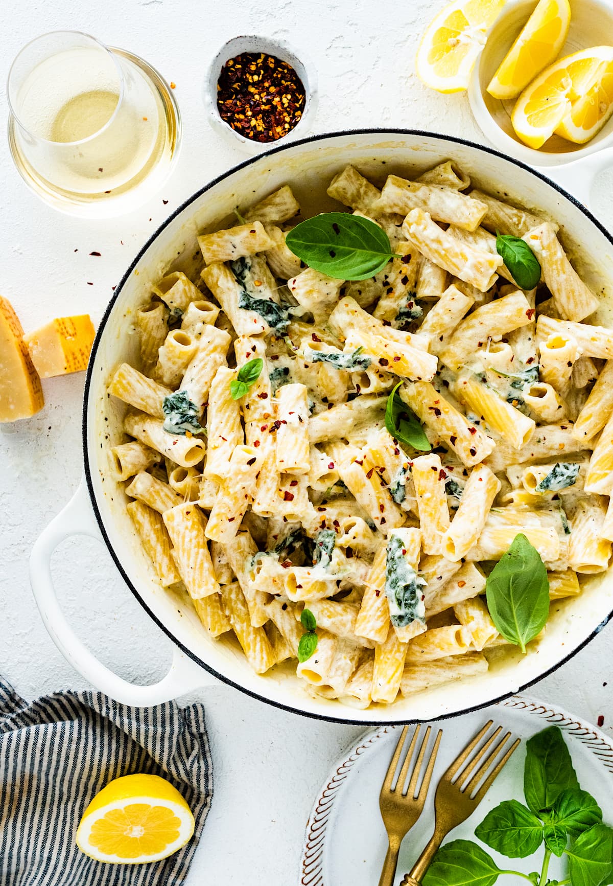 lemon ricotta pasta with crushed red pepper flakes and basil in large white pot. 