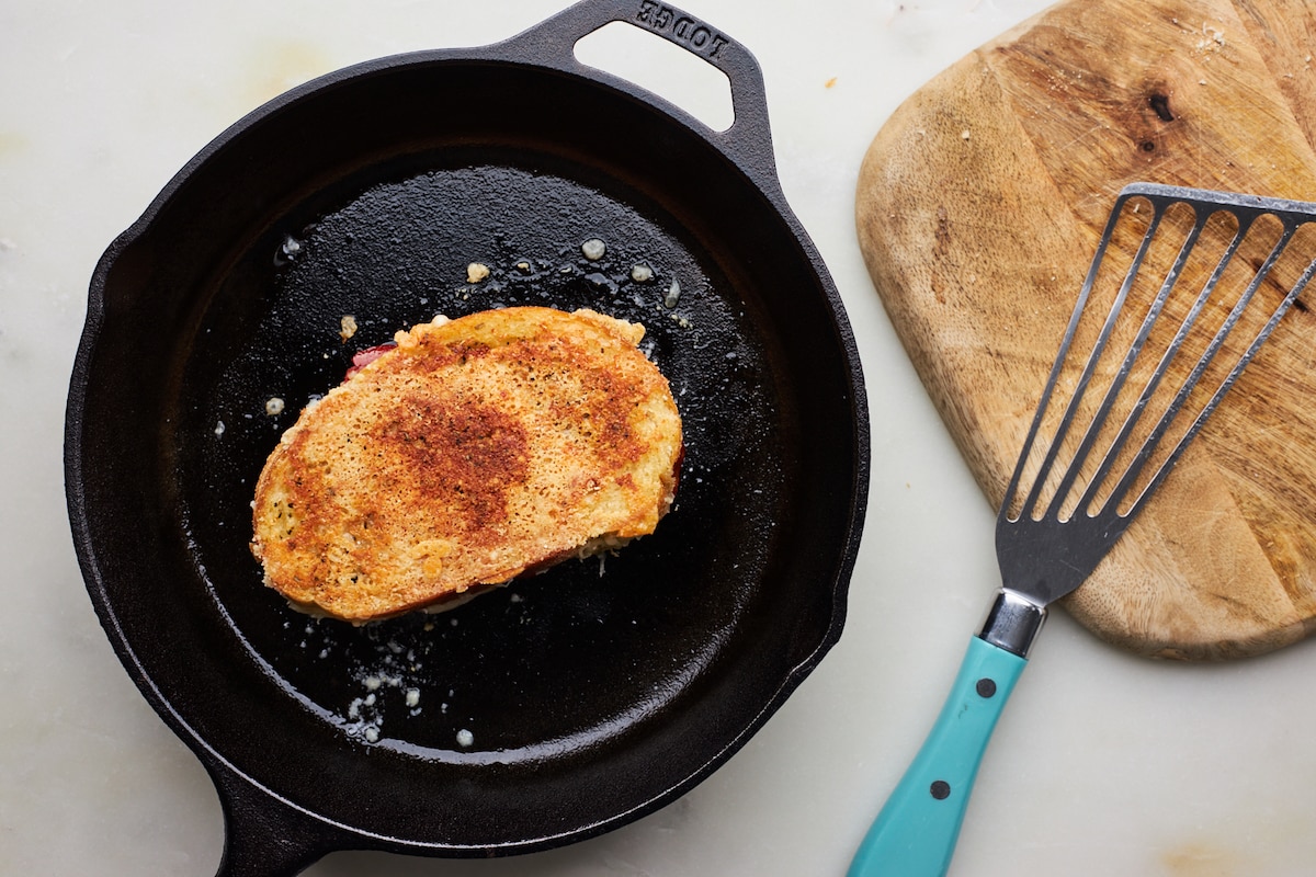 pizza grilled cheese cooking in cast iron skillet with spatula on the side. 