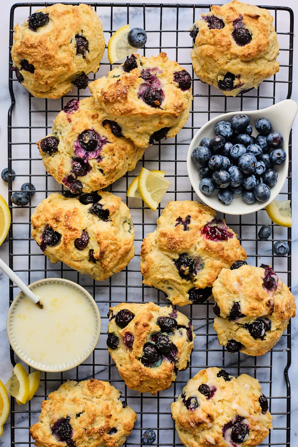 blueberry biscuits with fresh blueberries and lemon glaze on cooling rack. 