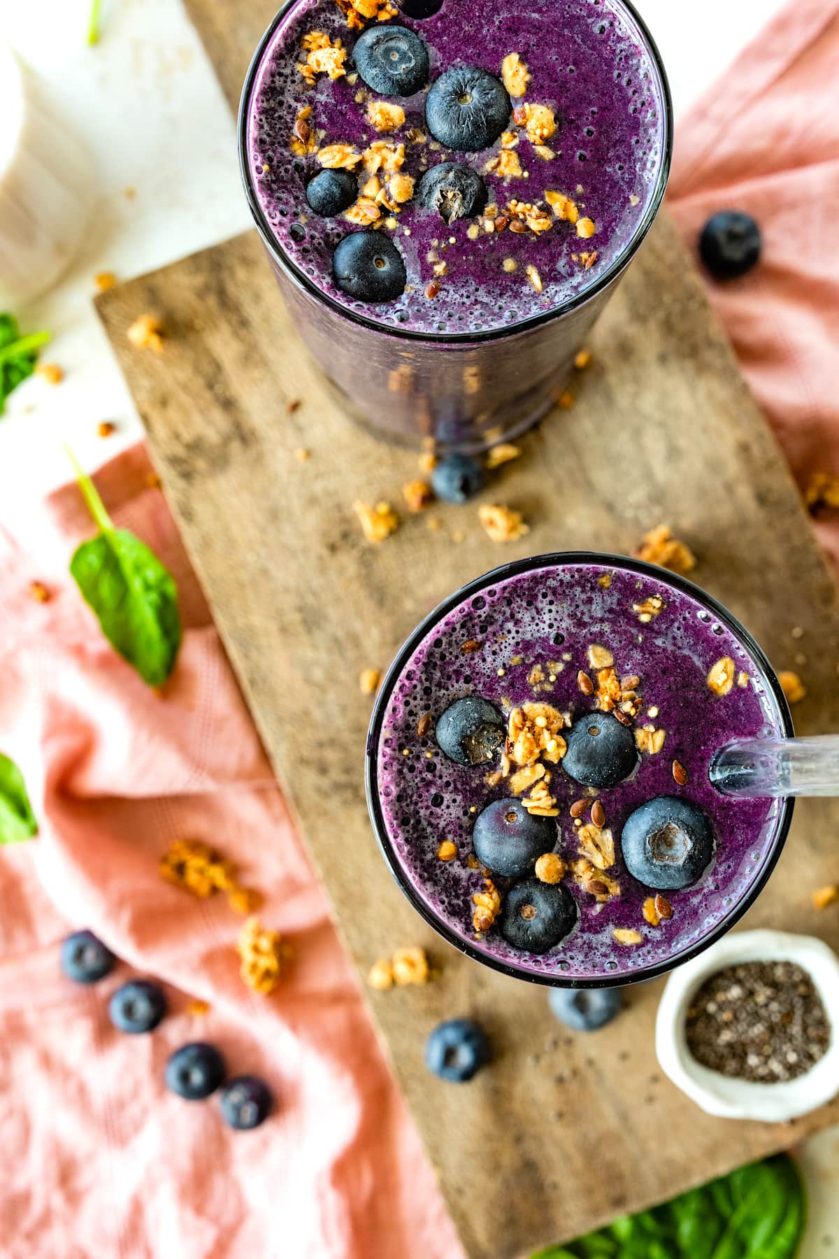 2 blueberry smoothies topped with fresh blueberries and granola.