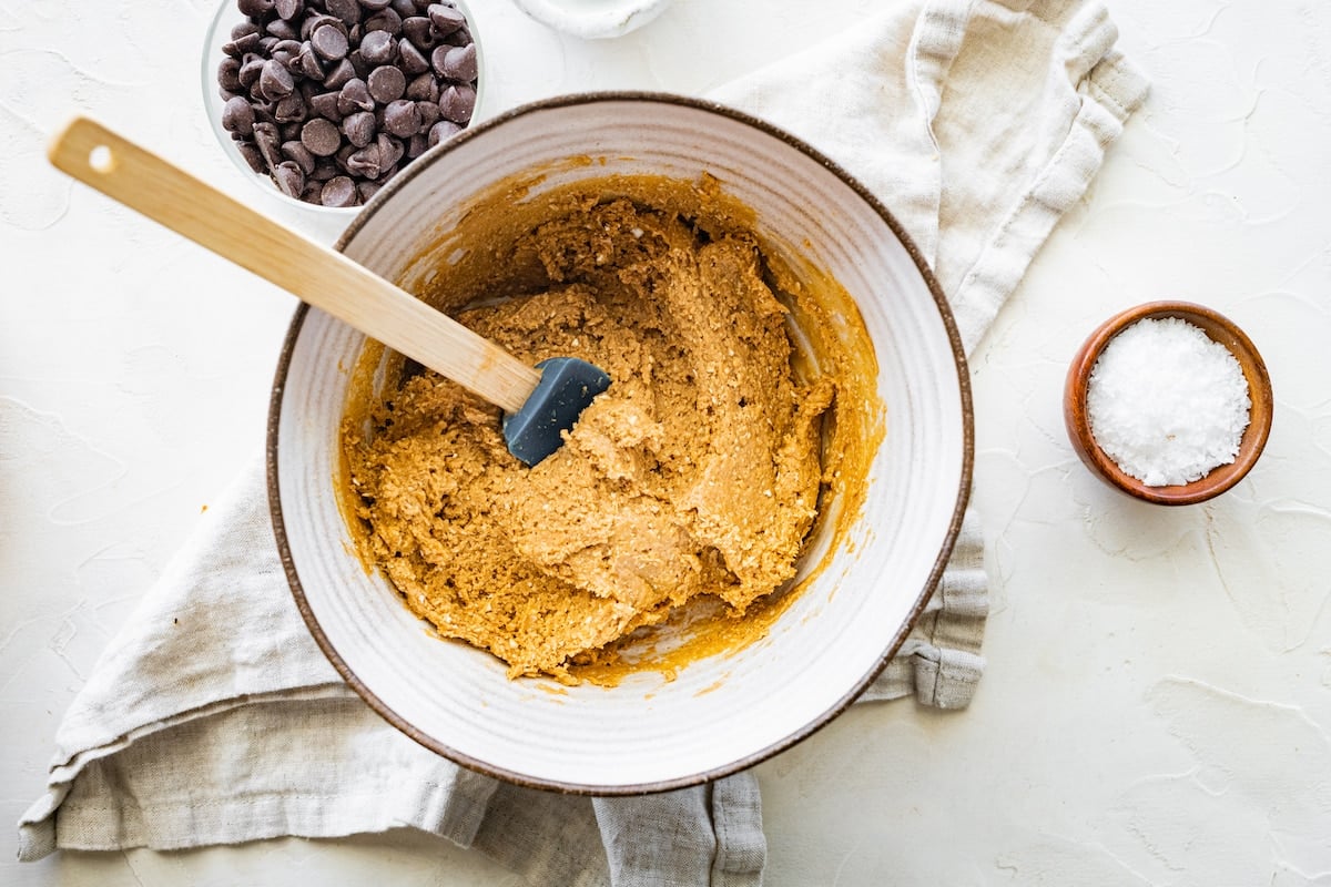 peanut butter protein balls mixture in mixing bowl with spatula. 