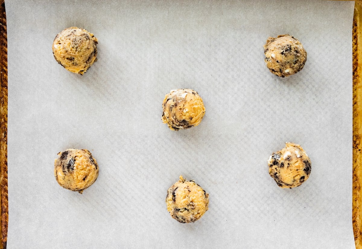 cookie dough balls on baking sheet lined with parchment paper. 