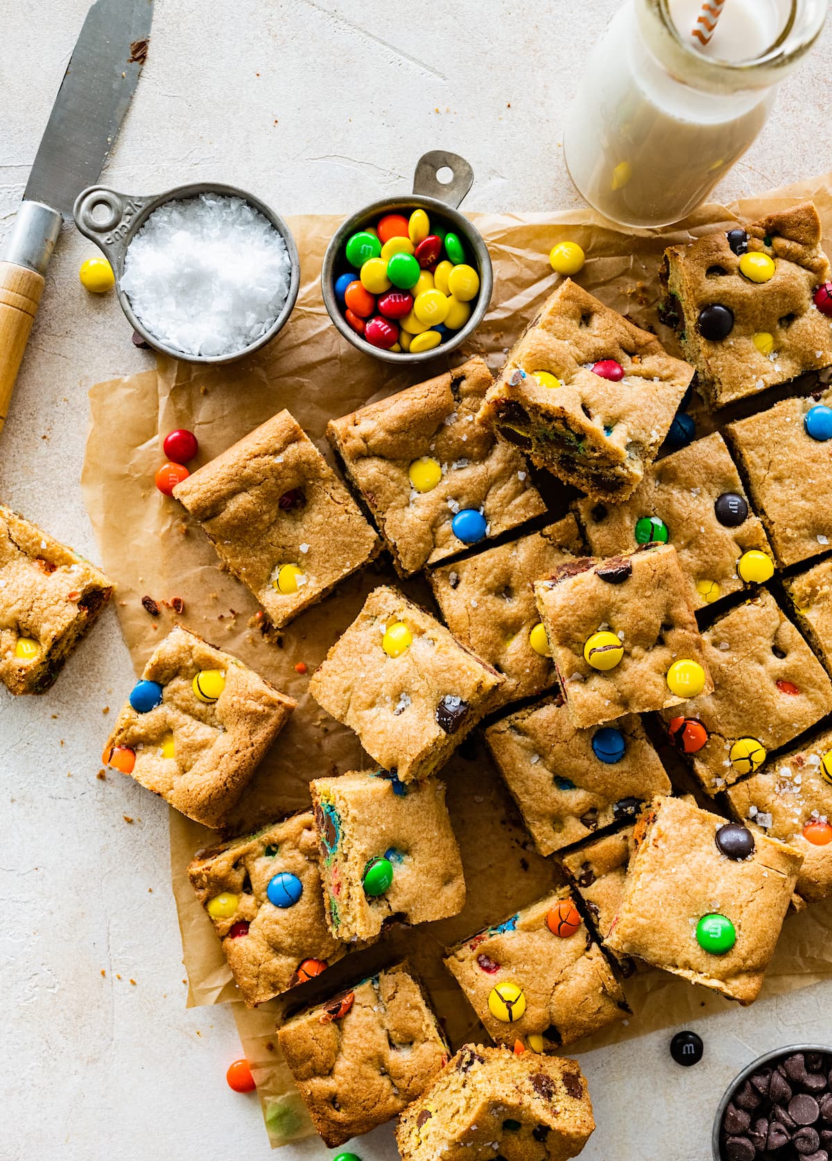 M&M Cookie Bars cut into squares on parchment paper with flaky sea salt. 