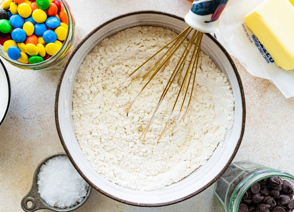 dry ingredients in bowl with whisk to make M&M cookie bars. 