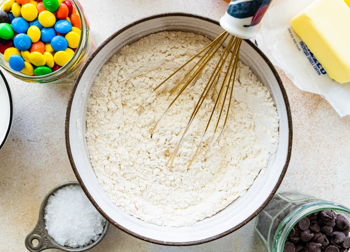 dry ingredients in bowl with whisk to make M&M cookie bars.
