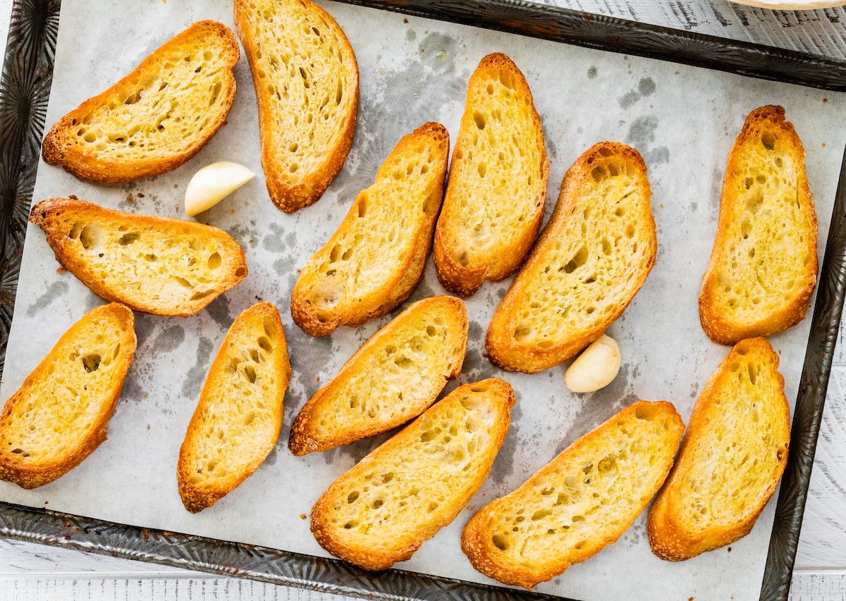 toasted baguette slices on baking sheet with parchment paper. 