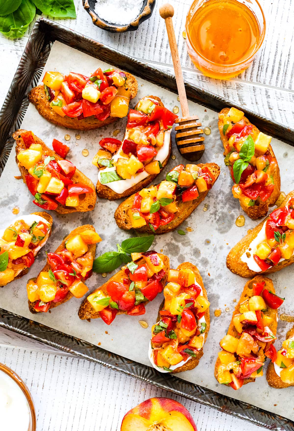 peach tomato bruschetta with fresh basil on baking sheet with parchment paper with honey. 
