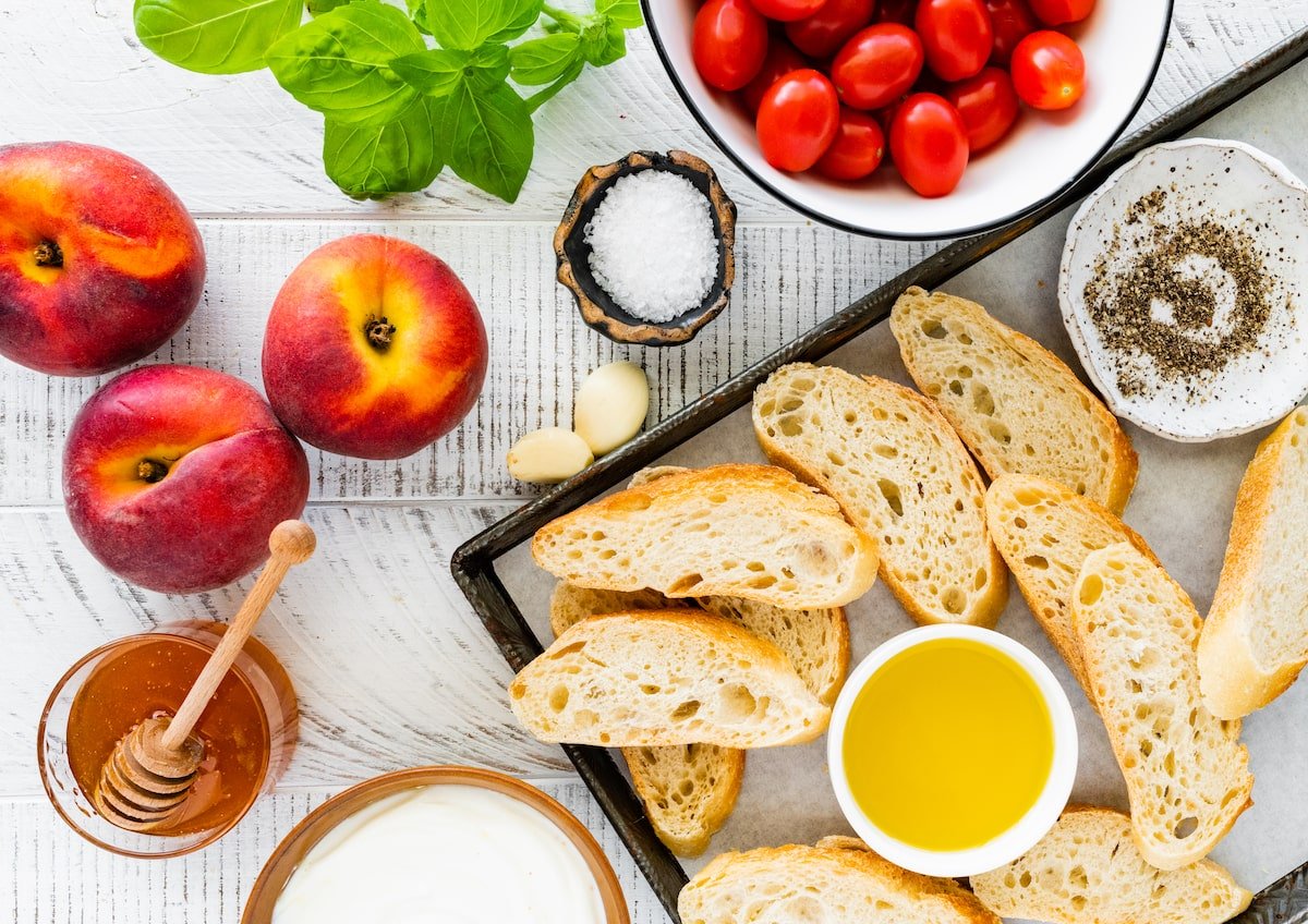 peaches, tomatoes, basil, bread slices, olive oil, and honey to make peach tomato bruschetta. 