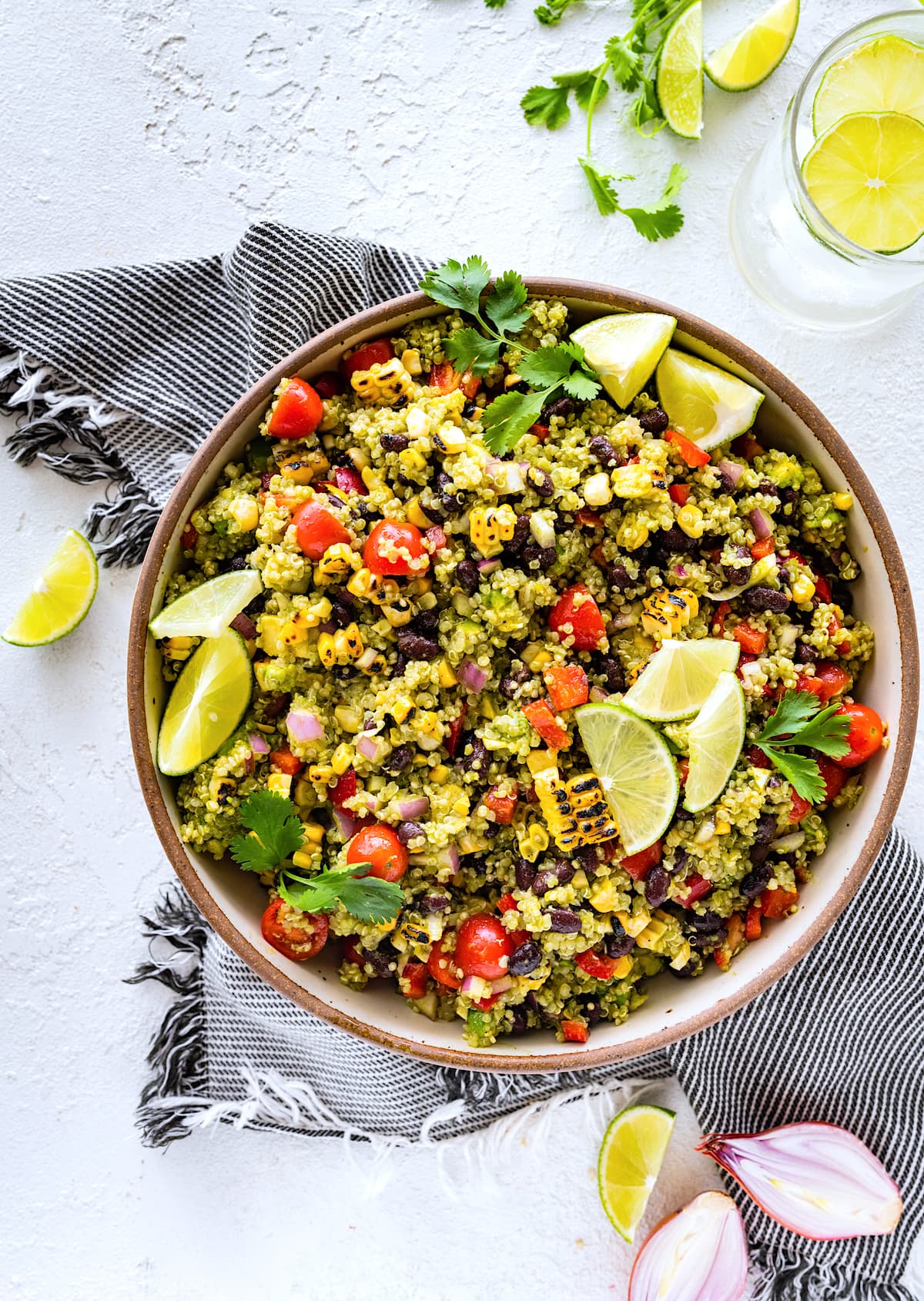 southwest quinoa salad with lime wedges and cilantro in large serving bowl with tea towel. 