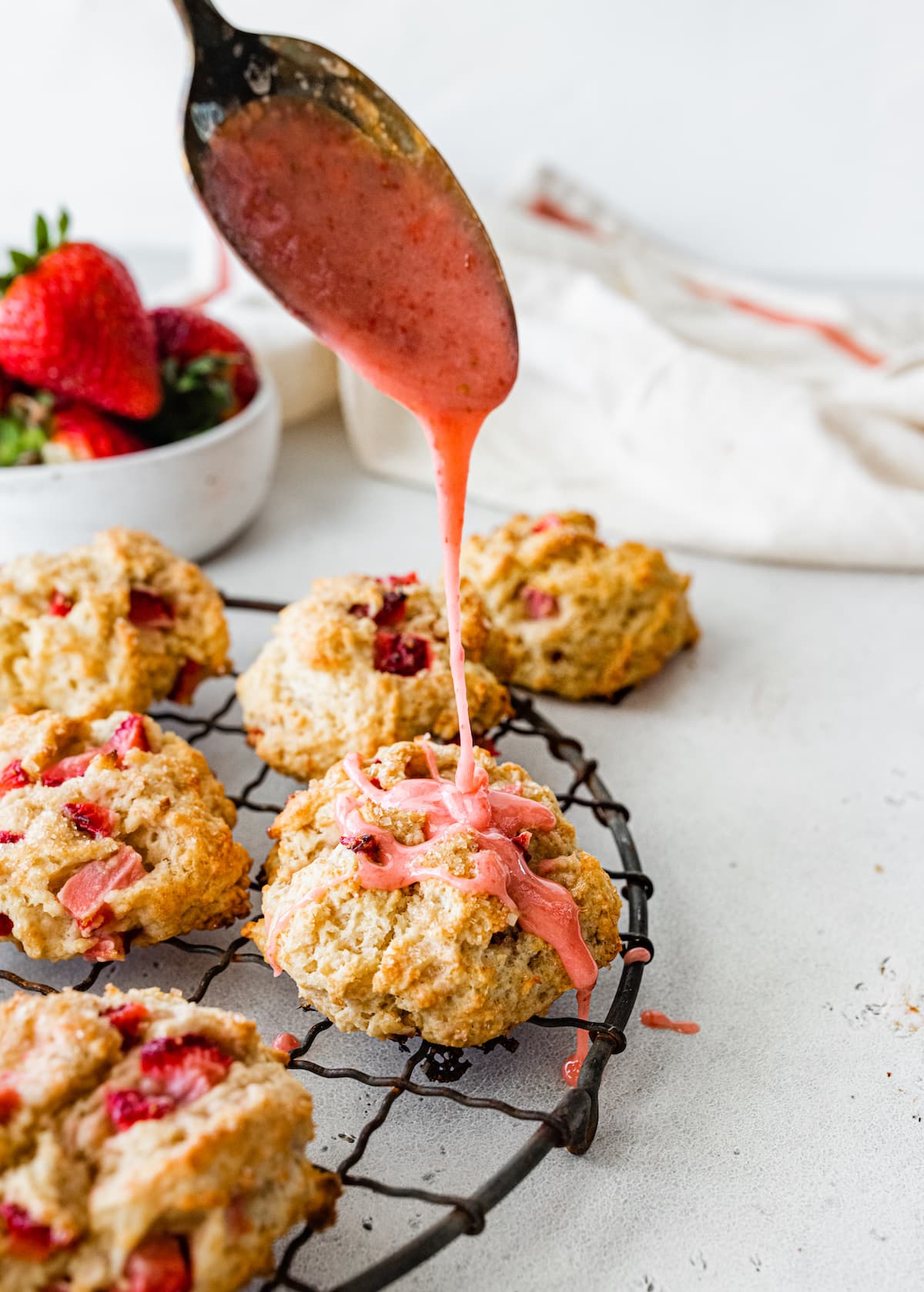 fresh strawberry glaze being drizzled over strawberry biscuits. 