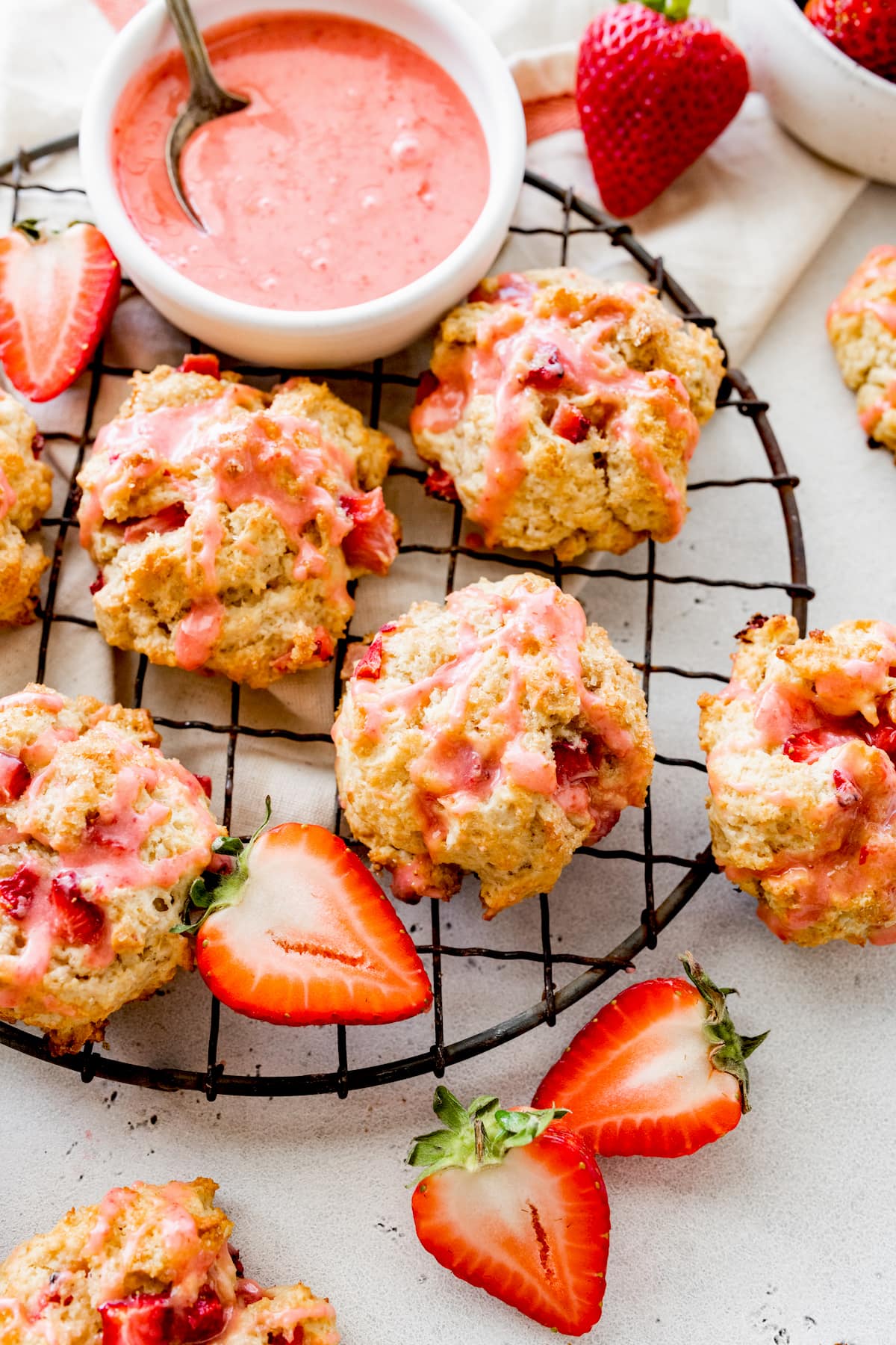 strawberry biscuits on cooling rack with fresh strawberry glaze in bowl. 