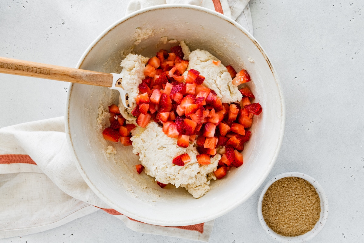 chopped strawberries being folded into biscuit batter in mixing bowl. 