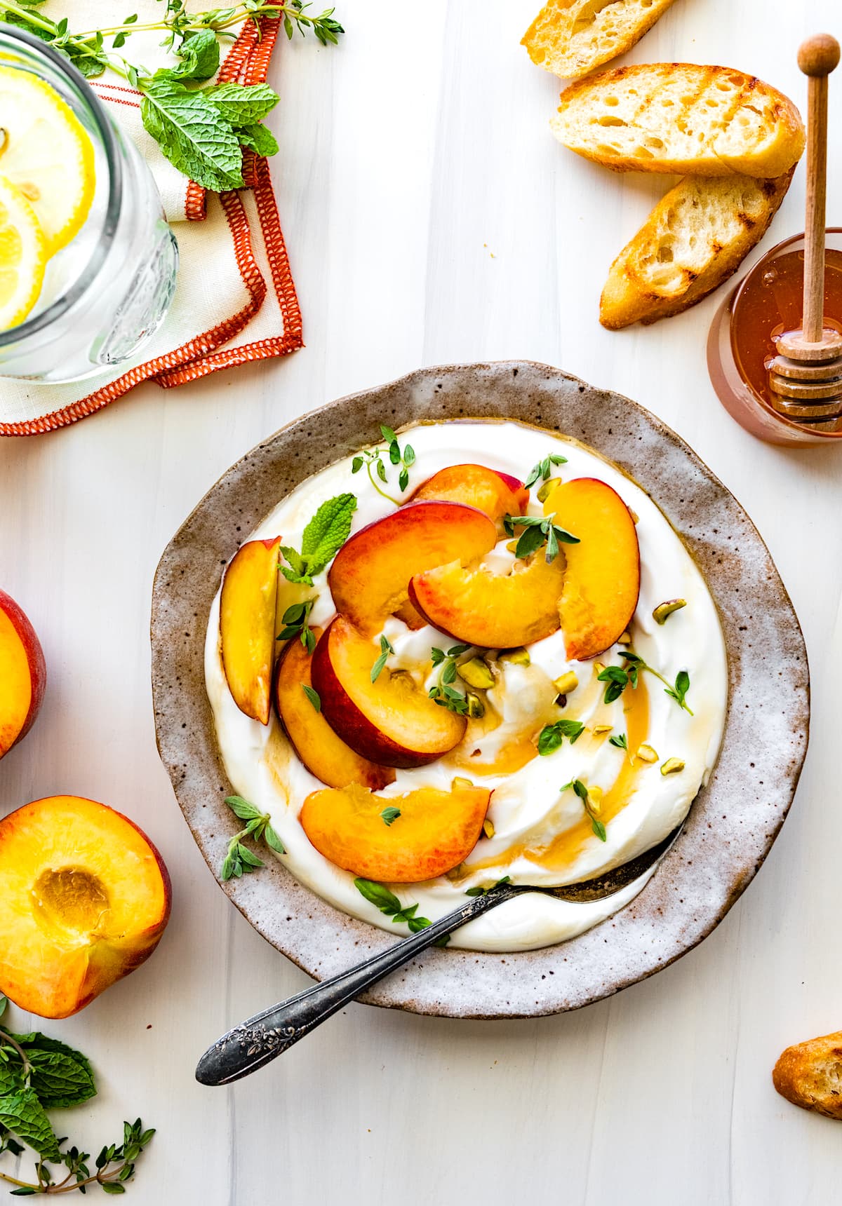 whipped cottage cheese in bowl with peach slices, honey, and pistachios. 