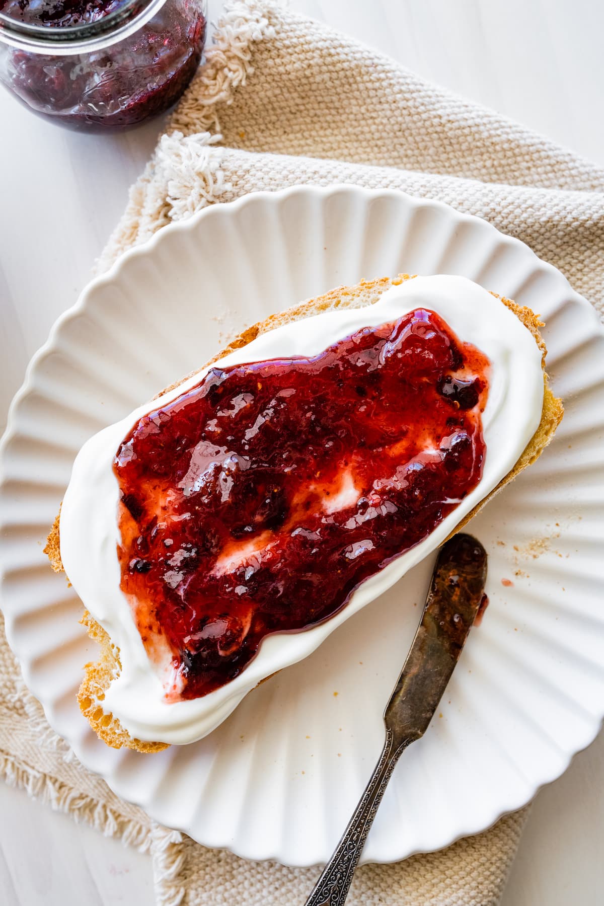 whipped cottage cheese with raspberry jam on toast on plate. 