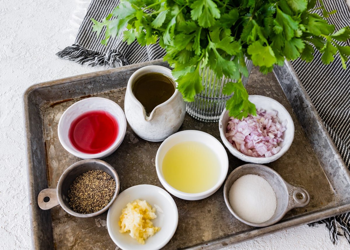 ingredients in bowls and bunch of cilantro in glass on tray ready to make cilantro lime vinaigrette. 