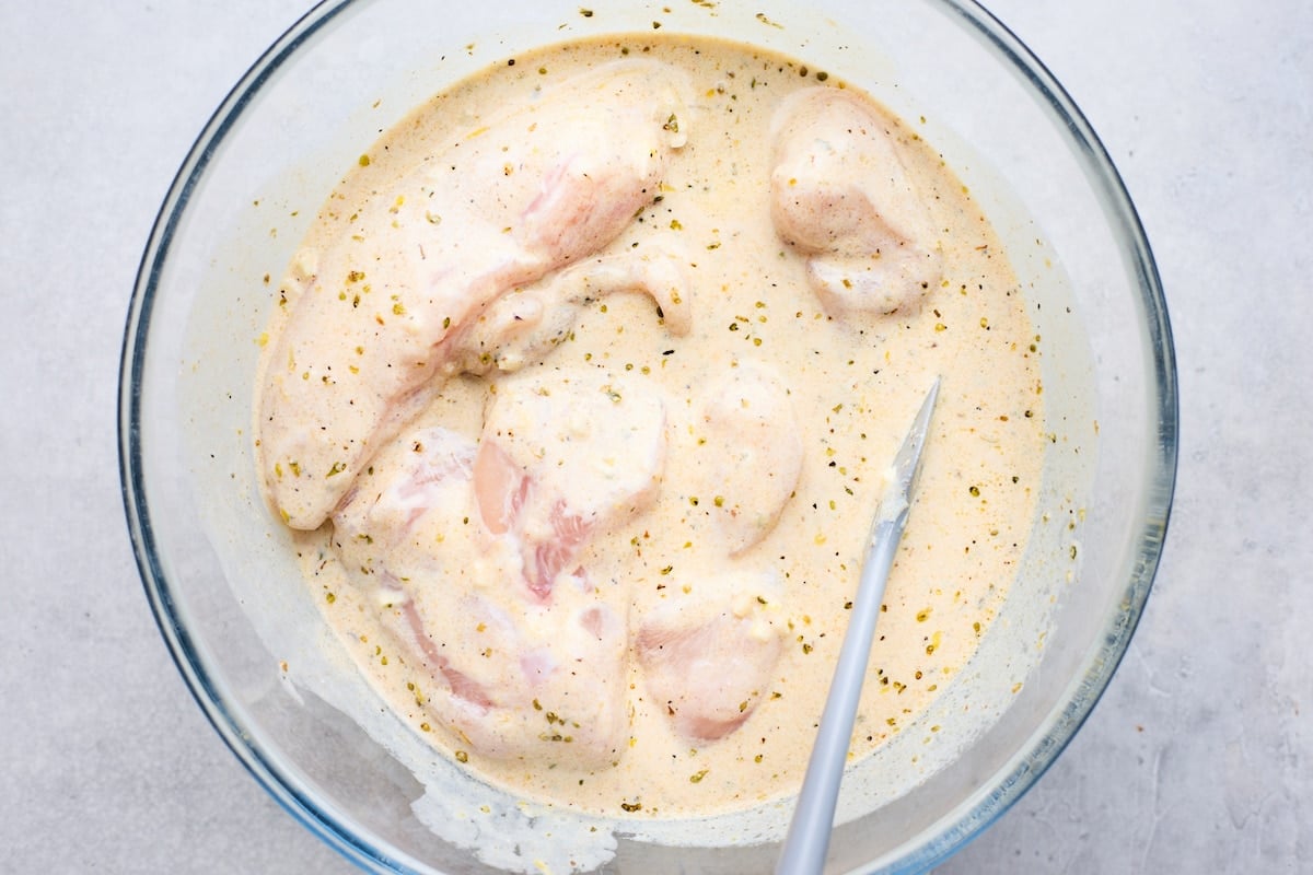 chicken in bowl with greek yogurt marinade. 