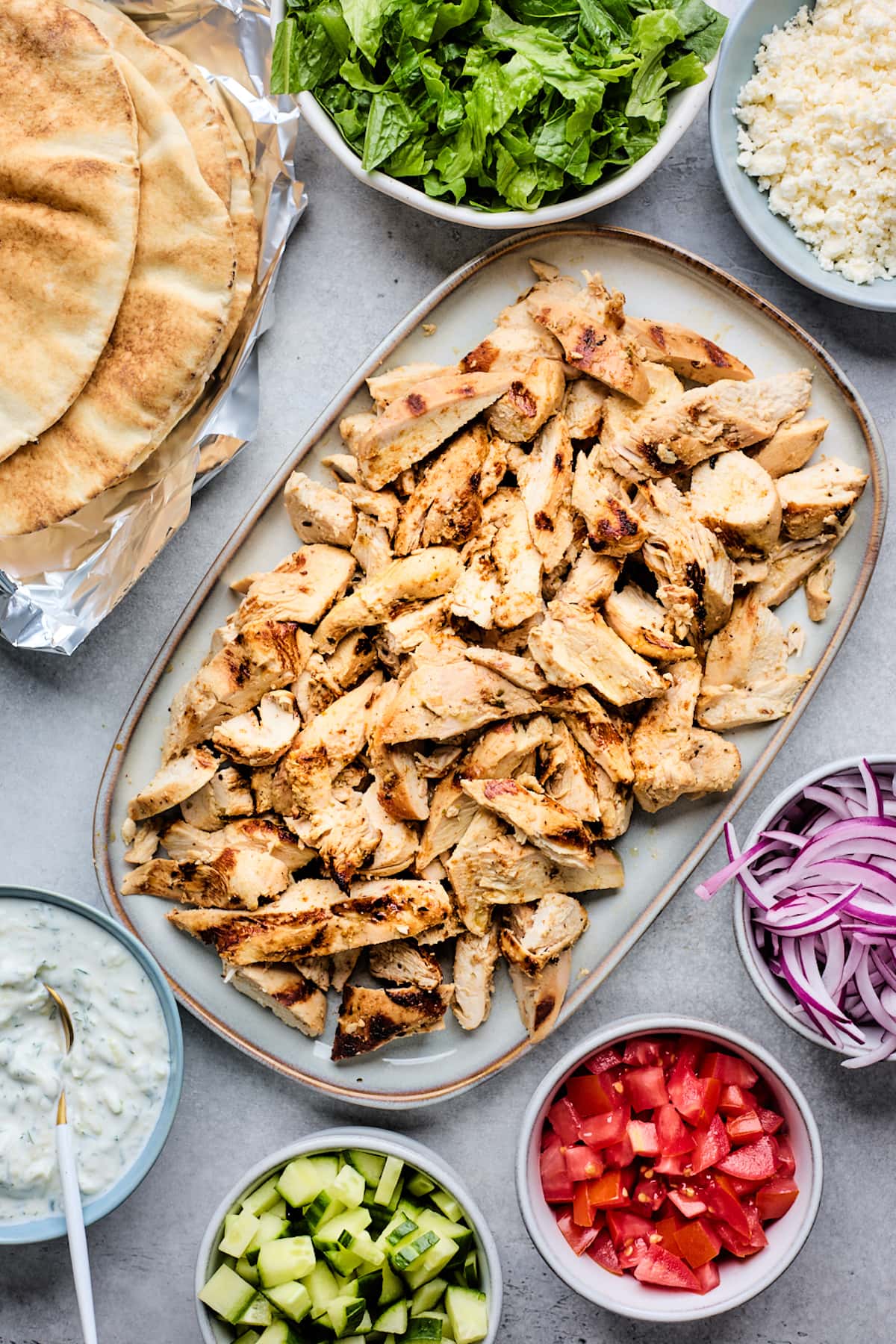 chopped chicken on platter with toppings to make chicken gyros. 