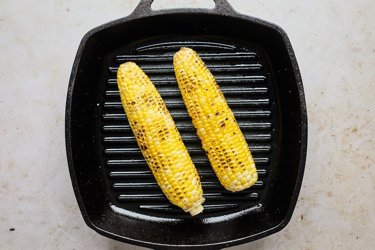 sweet corn being grilled on grill pan. 
