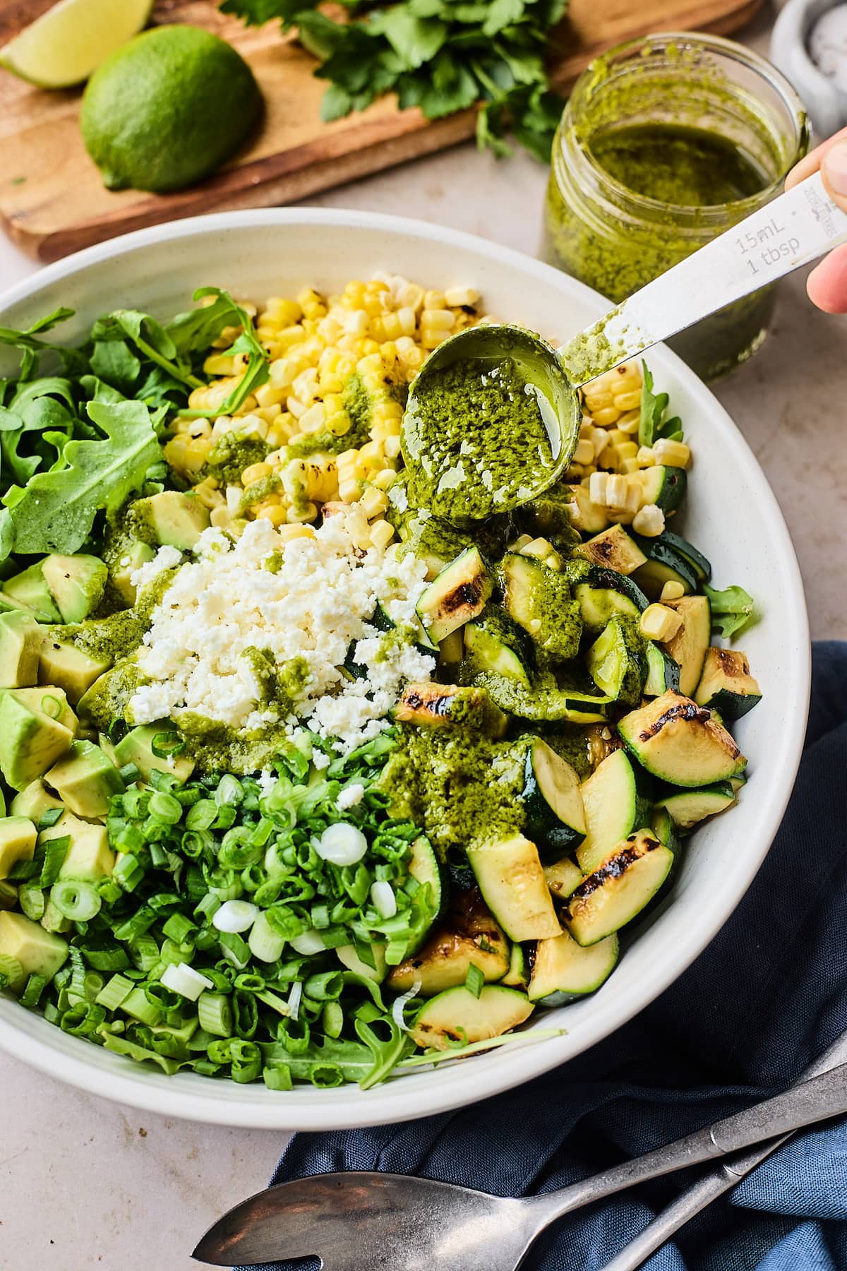 cilantro lime vinaigrette being drizzled over corn zucchini salad. 